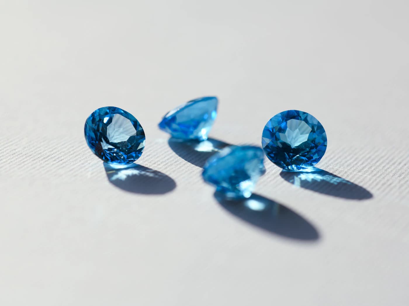 Loose faceted blue gemstones on a white surface
