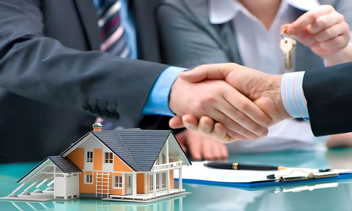 Buyer and agent shaking hands over a house model and keys